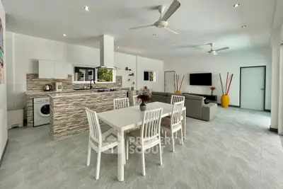Spacious open-plan living room with modern kitchen and dining area, featuring sleek design and ample natural light.