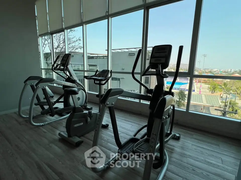 Modern gym with exercise equipment and large windows offering scenic views.