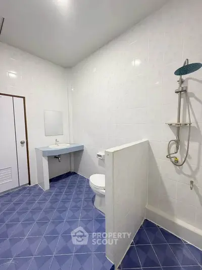 Spacious modern bathroom with blue tiled floor and sleek shower design