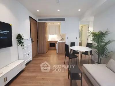 Modern living room with open kitchen, stylish furniture, and wooden flooring in a contemporary apartment.