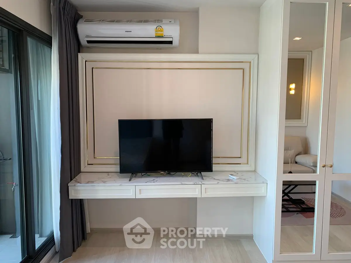 Modern living room with wall-mounted TV and air conditioner, sleek design and natural light.