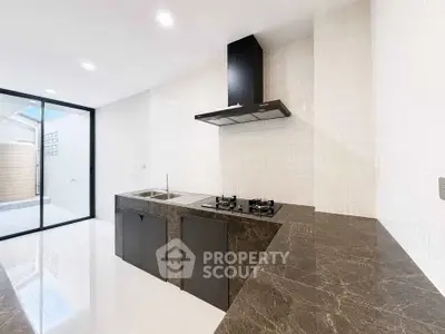 Modern kitchen with sleek black countertops and gas stove, featuring open layout and natural light.