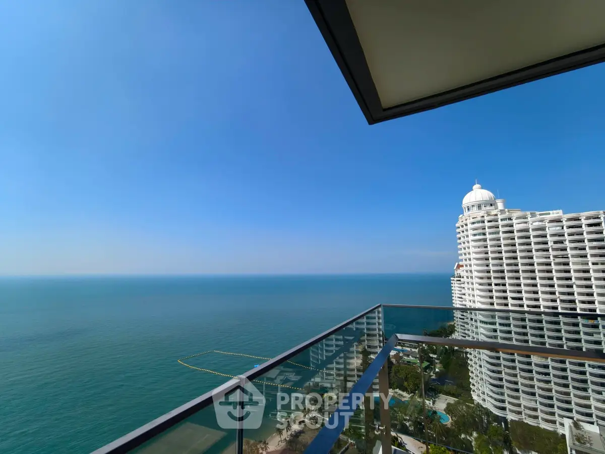 Stunning ocean view from a high-rise balcony with modern glass railing.