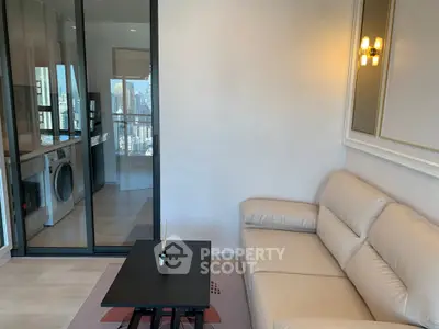 Modern living room with beige sofa and city view, featuring a sleek glass partition.