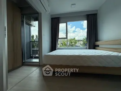 Modern bedroom with large window and balcony view, featuring minimalist design and natural light.