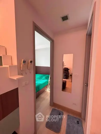 Cozy apartment hallway leading to a bedroom with modern decor and wooden flooring.
