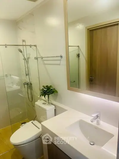 Modern bathroom with glass shower, sleek fixtures, and elegant design.