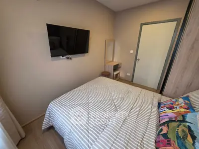 Cozy bedroom with modern decor and wall-mounted TV, perfect for relaxation.