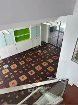 Spacious modern living room with unique carpet design and glass railing, perfect for stylish urban living.