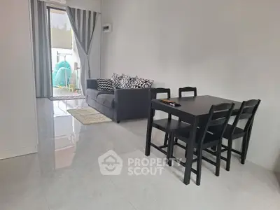 Modern living room with sleek black furniture and access to a bright balcony.