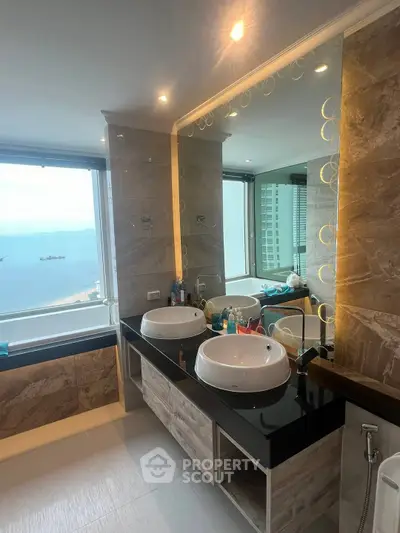 Luxurious bathroom with dual sinks and ocean view in high-rise apartment.