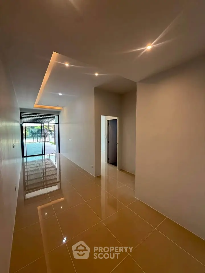 Spacious modern hallway with glossy tiles and recessed lighting leading to a pool view.
