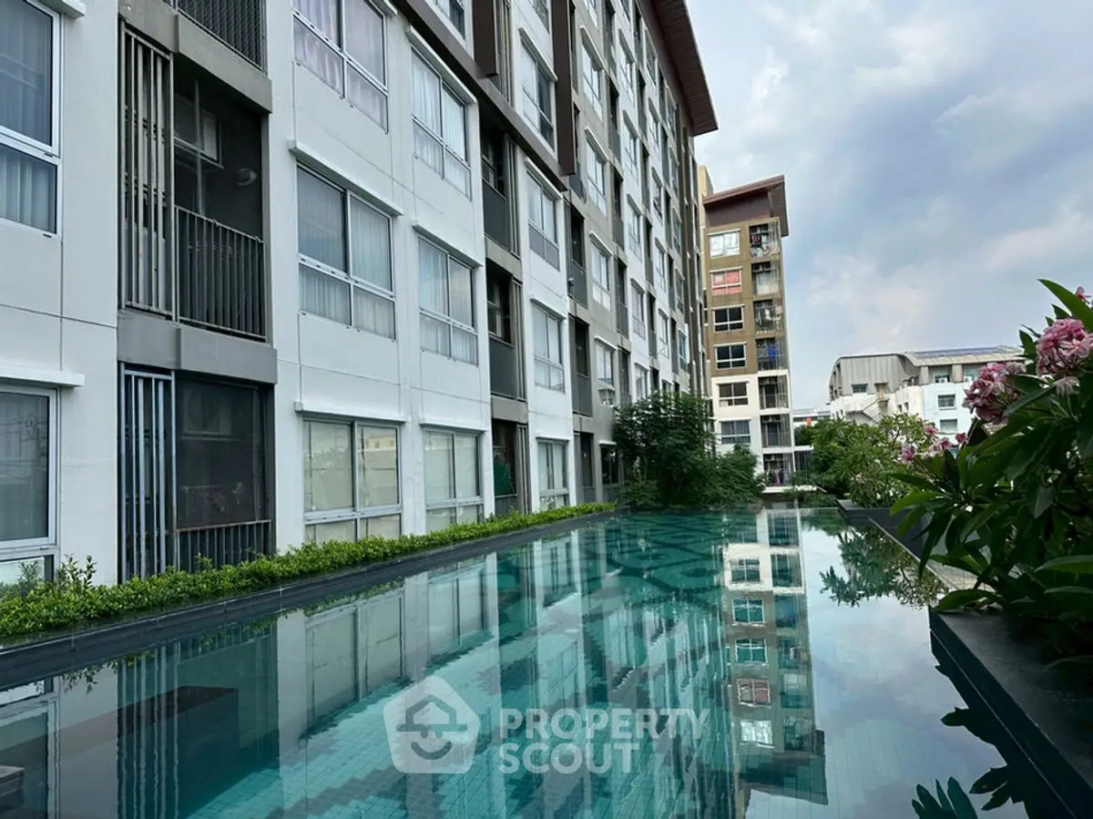 Modern apartment building with a serene pool and lush greenery, perfect for urban living.