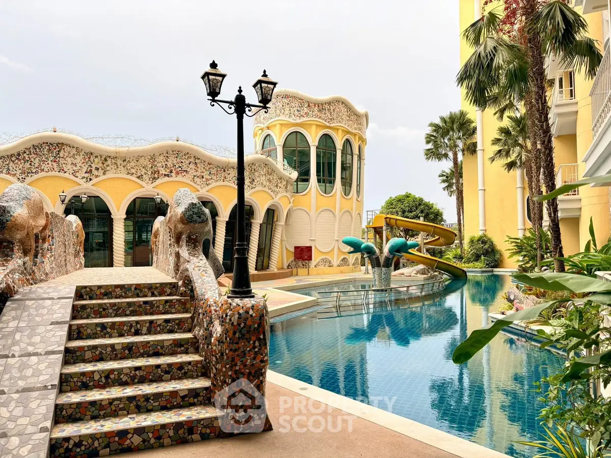 Luxurious pool area with unique architecture and slide, surrounded by lush greenery and elegant buildings.