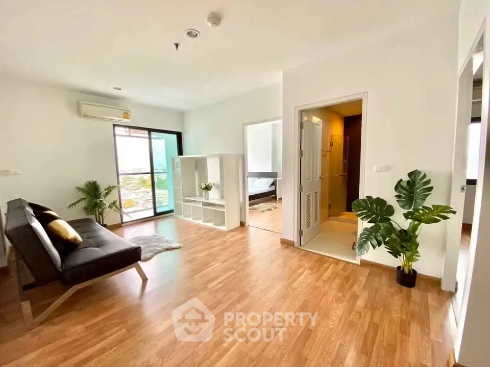 Spacious modern living room with wooden flooring and balcony access in a stylish apartment.