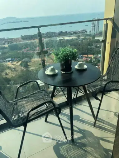 Stunning balcony view with cozy seating overlooking the ocean and cityscape.