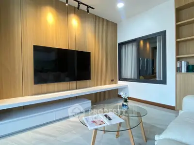 Modern living room with sleek TV setup and stylish glass coffee table.