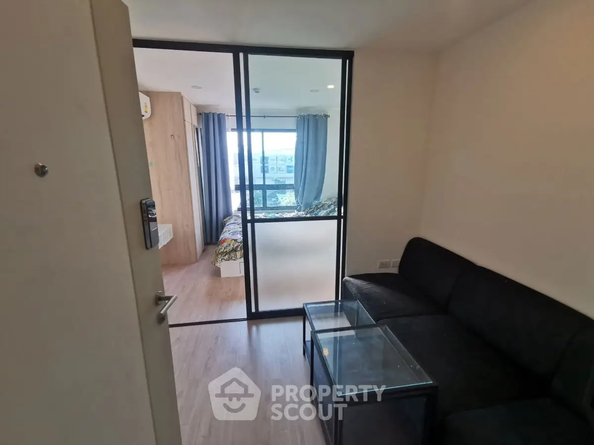 Modern apartment interior with glass partition, cozy living room, and bright bedroom view.