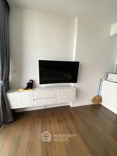 Modern living room with wall-mounted TV and stylish cabinet on wooden flooring.