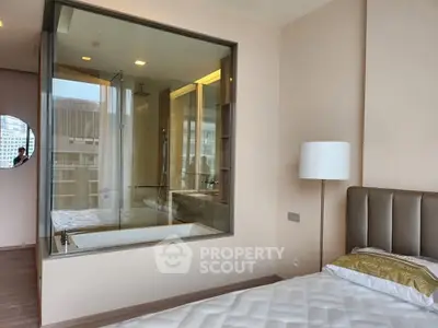 Modern bedroom with glass-enclosed bathtub offering urban views