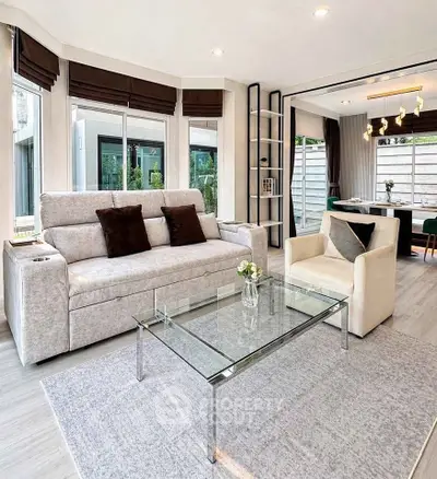 Modern living room with elegant furniture and large windows offering natural light.