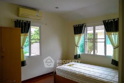 Cozy bedroom with natural light and air conditioning, perfect for relaxation.