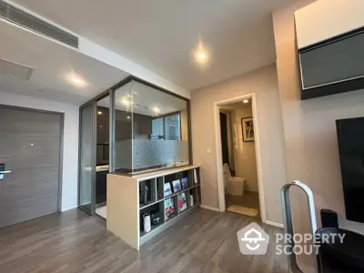 Modern apartment interior with open layout kitchen, sleek cabinetry, and ample lighting, leading to a cozy bedroom and well-appointed living space.