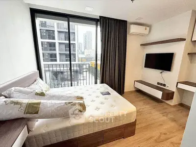Modern bedroom with large window and city view, featuring a wall-mounted TV and stylish decor.