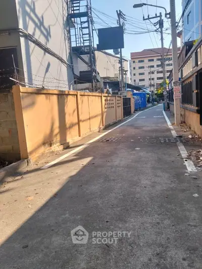 Urban alleyway with surrounding buildings and utility structures, showcasing city living environment.