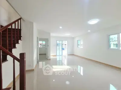 Spacious modern living room with natural light and staircase in a bright home