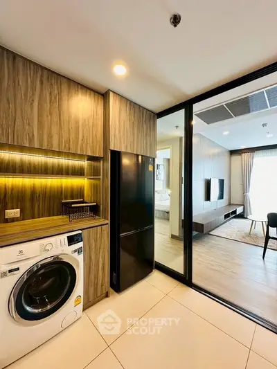 Modern apartment interior with sleek kitchen and open living area, featuring stylish wood finishes and natural lighting.