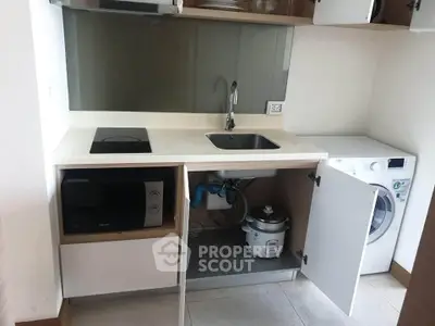 Compact kitchen with modern appliances including microwave, washing machine, and induction cooktop.
