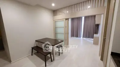 Modern dining area with sleek table and bench, leading to a cozy living space with curtains.