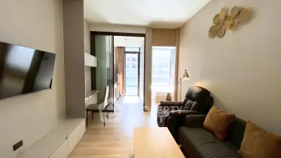 Modern living room with sleek design and natural light, featuring a cozy seating area and wall-mounted TV.