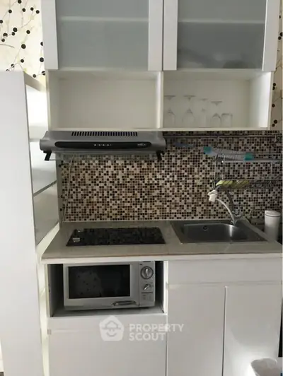 Compact modern kitchen with mosaic backsplash and built-in appliances