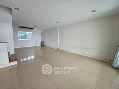 Spacious empty living room with tiled flooring and air conditioning, ready for customization.