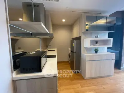 Modern kitchen with sleek appliances and wooden cabinetry in a stylish apartment.