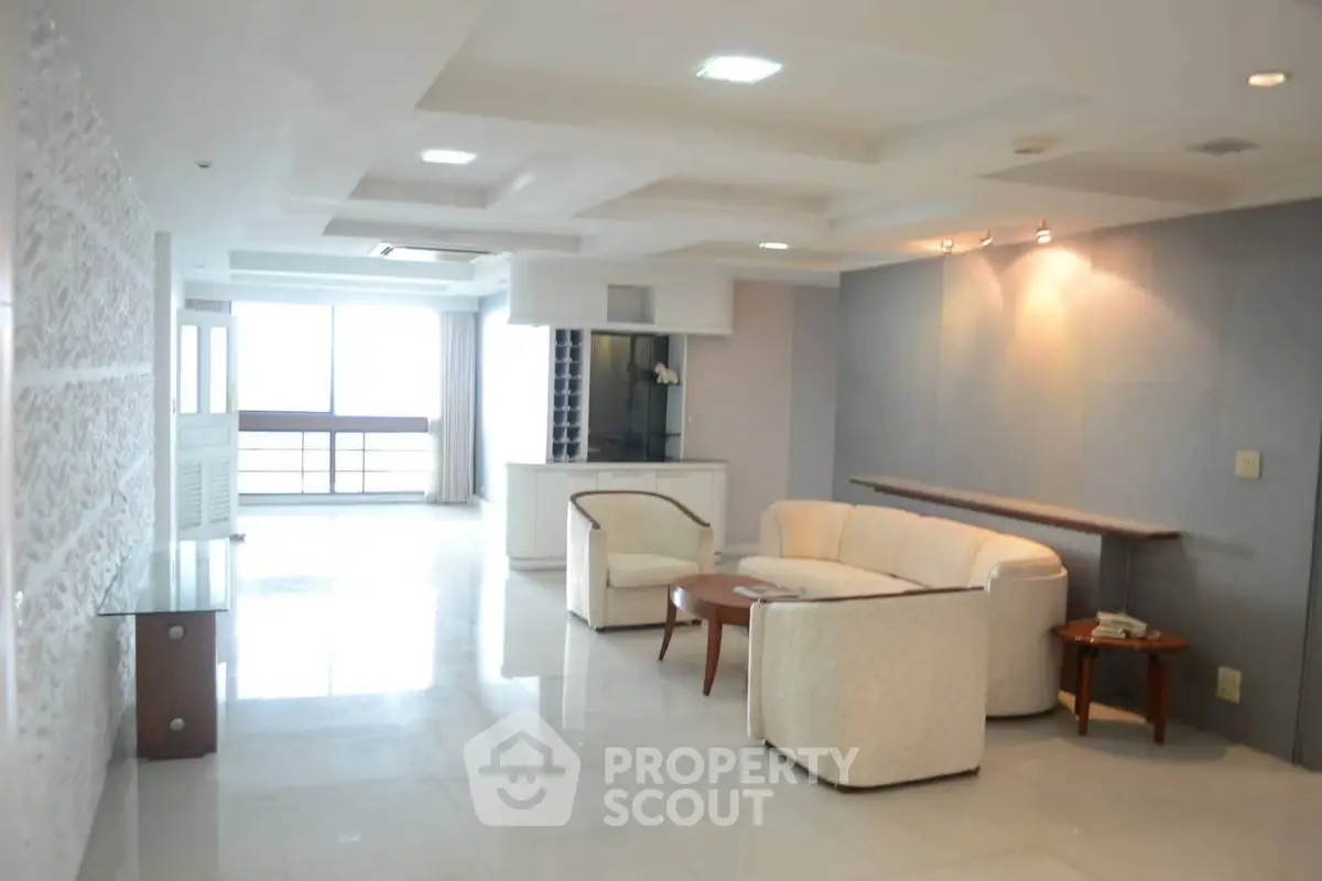 Spacious modern living room with elegant white furniture and ample natural light.