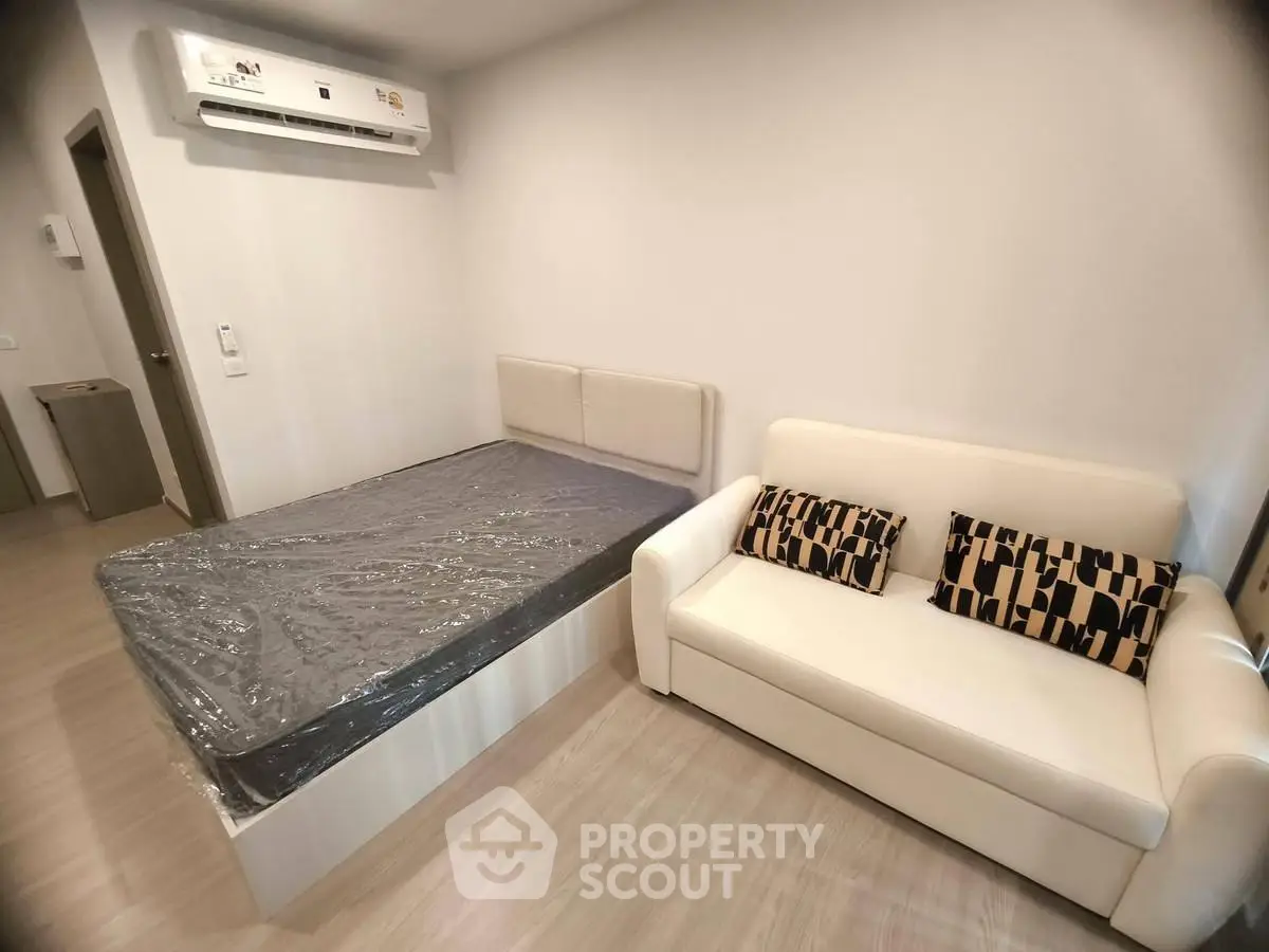 Modern bedroom with bed, sofa, and air conditioning in a cozy apartment.