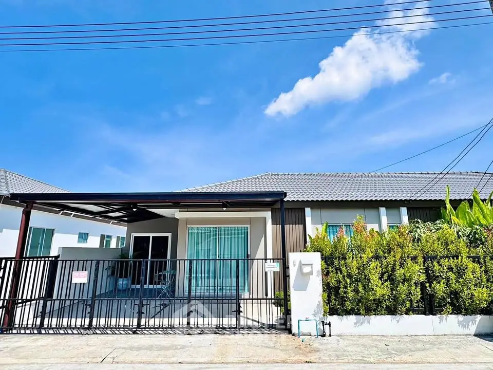 Charming single-story house with modern facade and lush greenery under a clear blue sky.