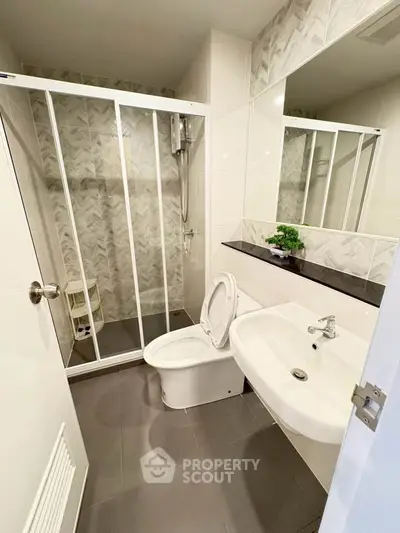 Modern bathroom with sleek shower and stylish sink in contemporary apartment.