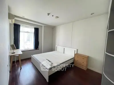 Spacious bedroom with modern furnishings and large window offering natural light.