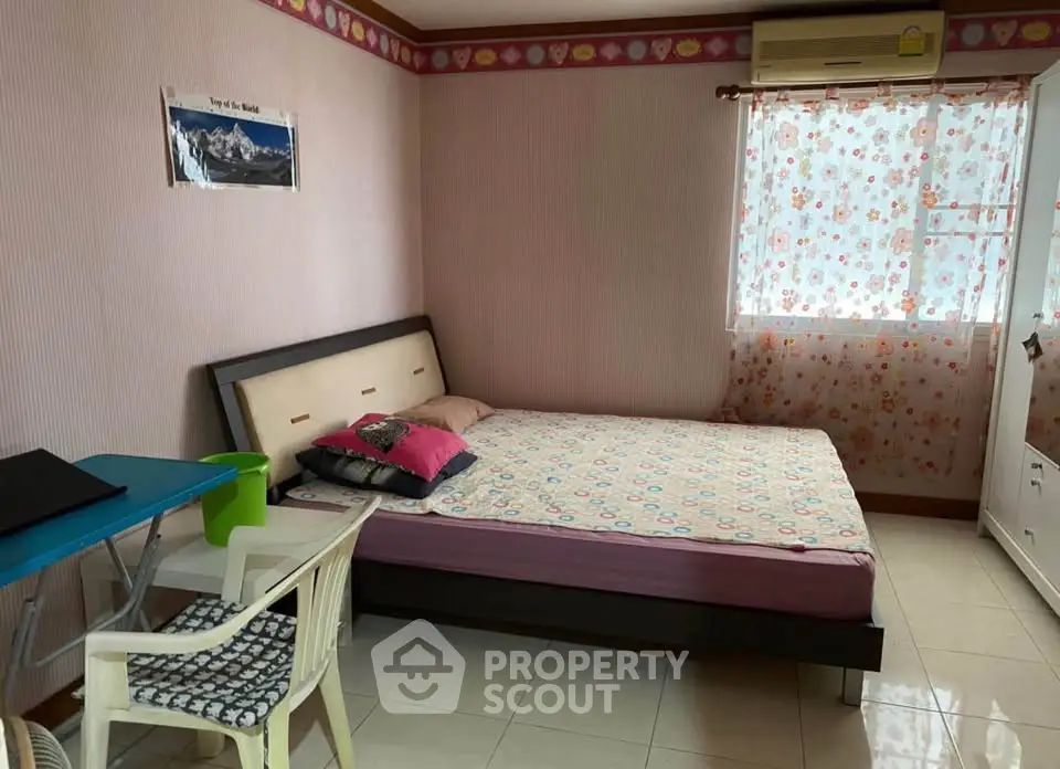Cozy bedroom with double bed, floral curtains, and air conditioning in a well-lit space.