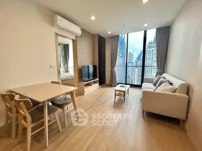 Modern living room with city view, featuring sleek furniture and large windows.