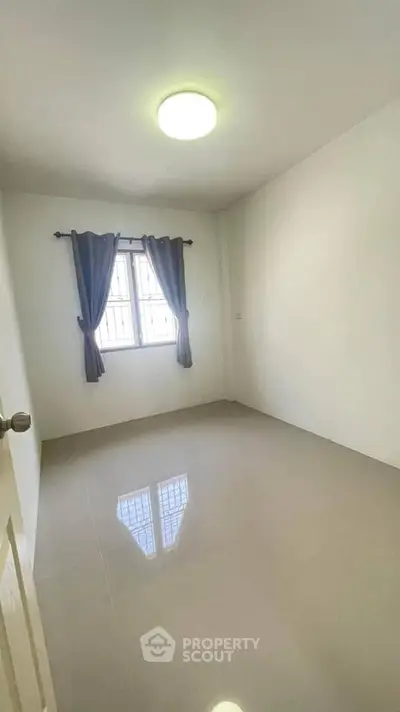 Spacious empty room with window and curtains, ideal for customization.
