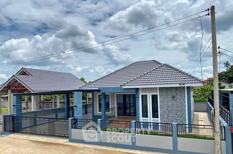 Modern single-story house with tiled roof and spacious driveway under a cloudy sky.