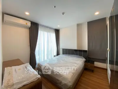 Modern bedroom with large window and wooden flooring in a stylish apartment.