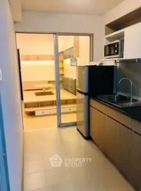 Modern kitchen with sleek cabinetry and open layout leading to cozy living area.