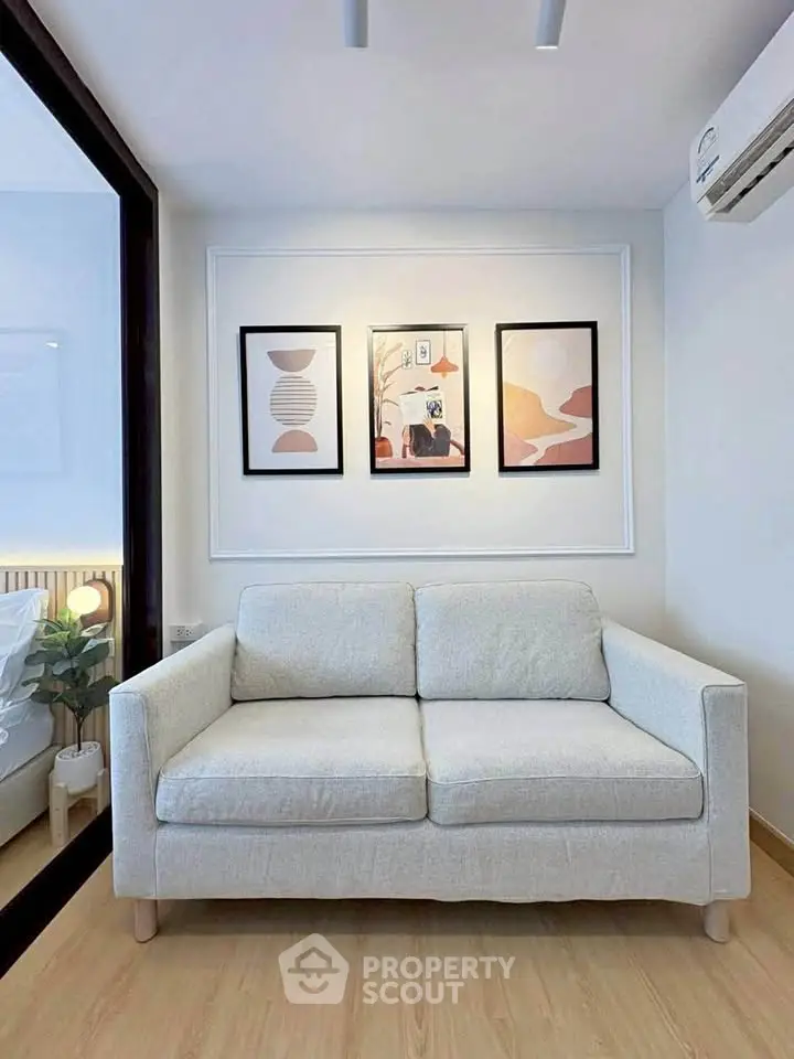 Modern living room with stylish sofa and wall art, featuring a glimpse of a cozy bedroom.
