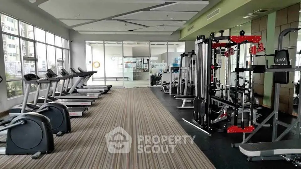 Spacious modern gym with state-of-the-art equipment and large windows for natural light.